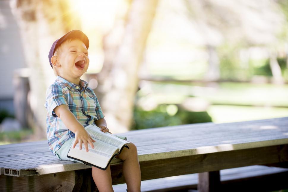 Happy child laughing while reading a book with pure joy