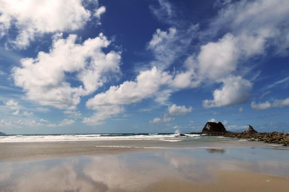 Free Image of Sunny beach with blue skies and white clouds 