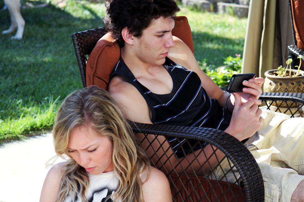 Free Image of Teenagers engrossed in phones on sunny day 