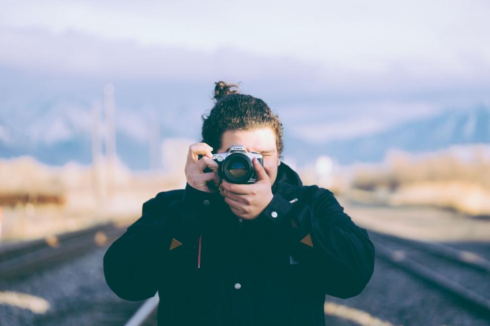 Free Image of Man taking a photo on train tracks 