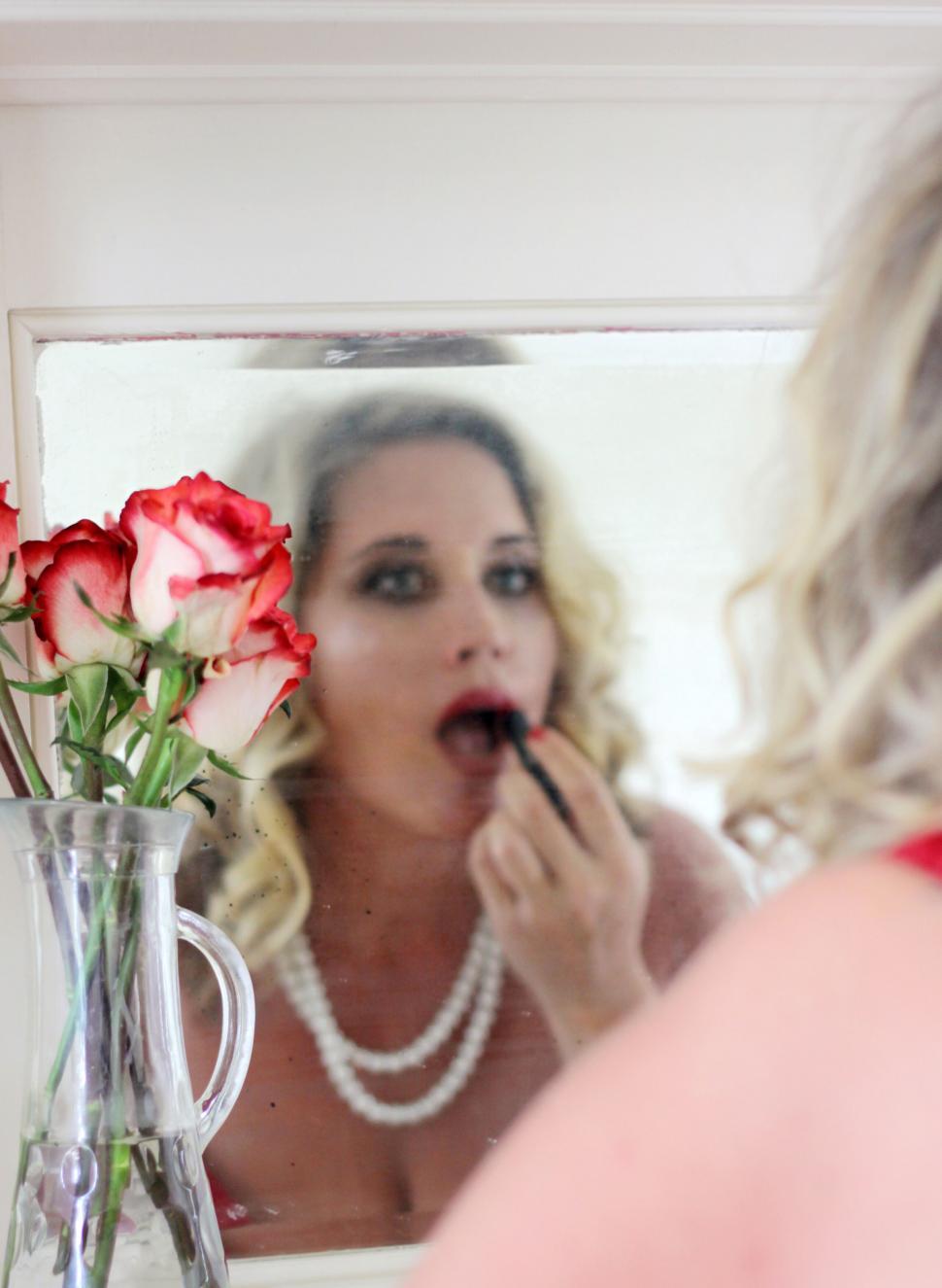 Free Image of Woman applying makeup with flowers 