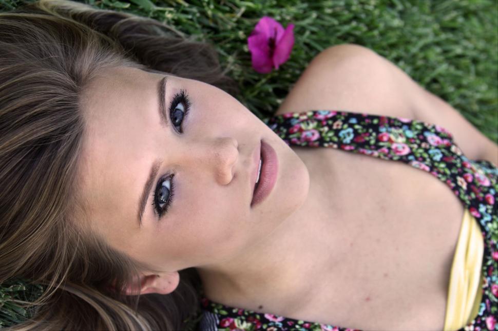 Free Image of Woman lying in a grassy field with flower 
