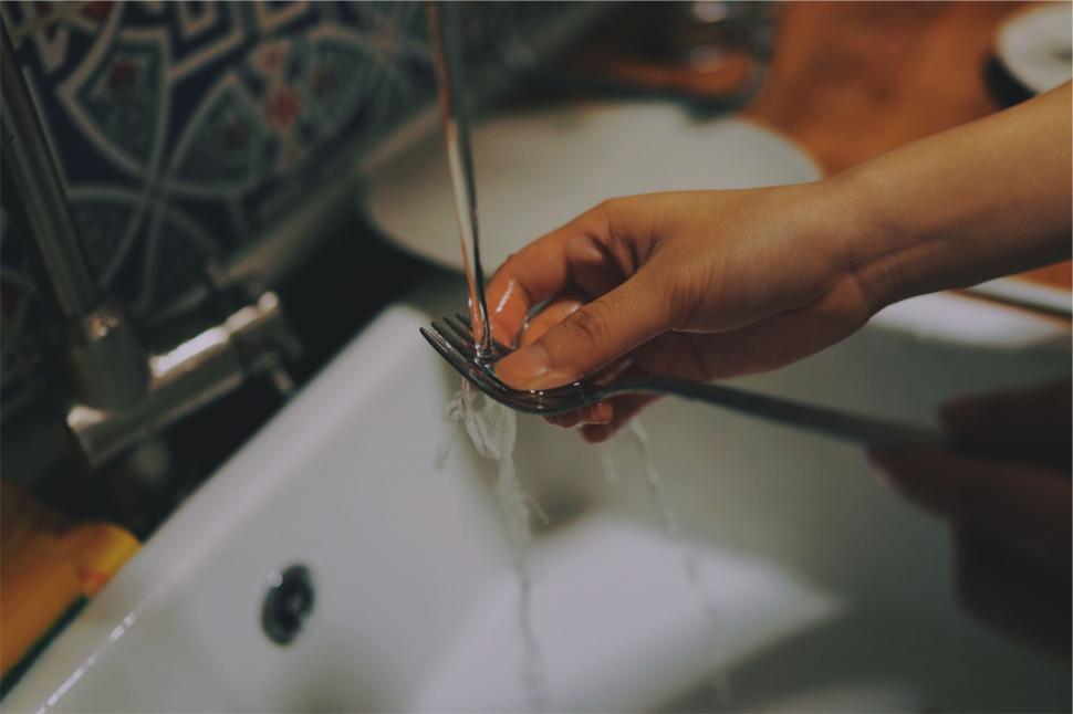 Free Image of Hand washing silverware under running water 