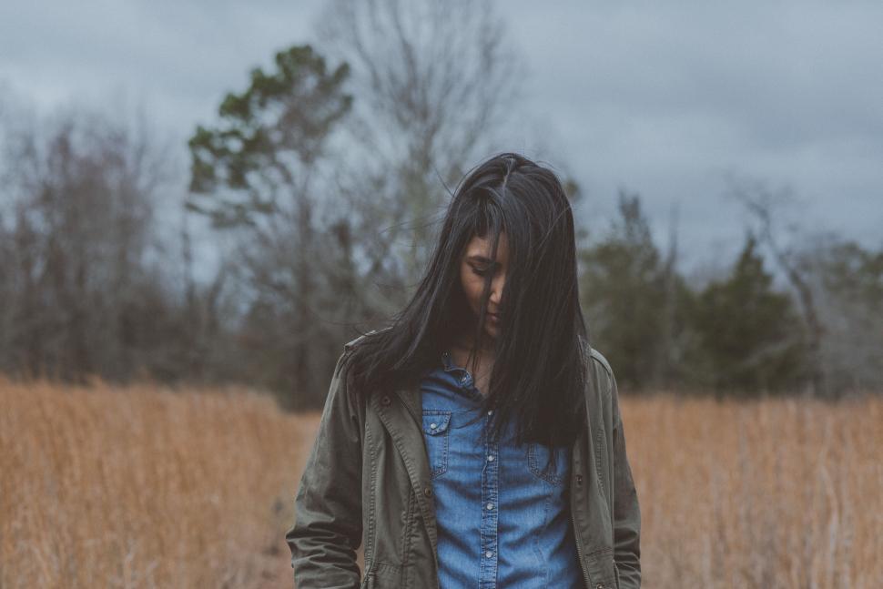 Free Image of Person in a field with hair covering face 
