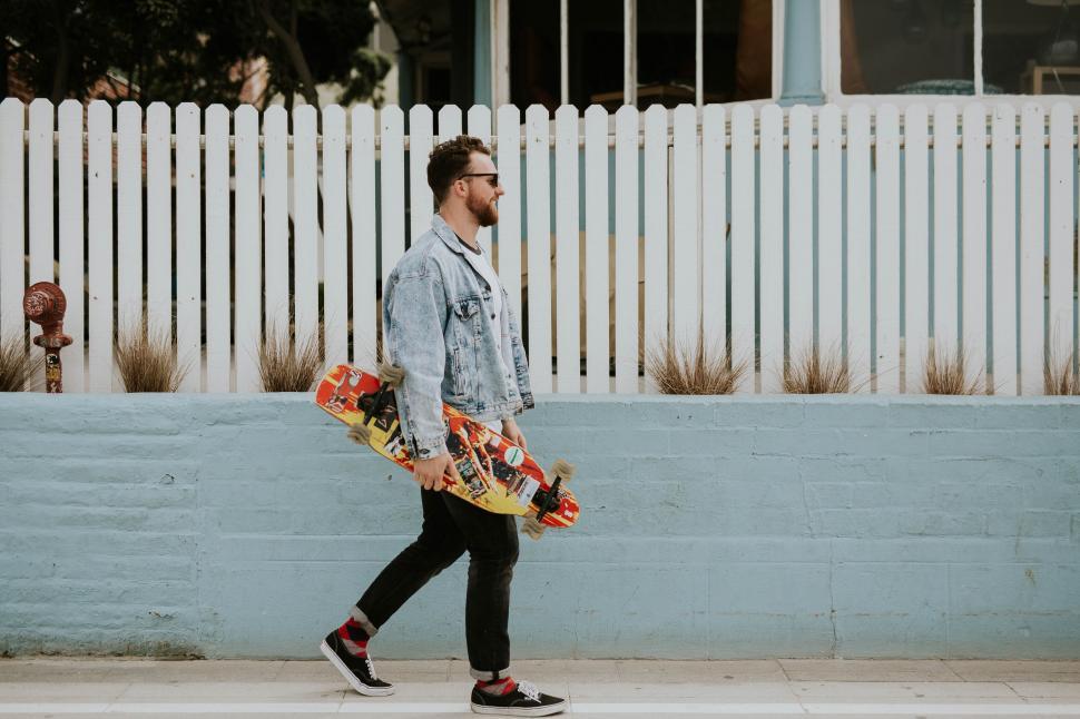 Free Image of Skateboarder in motion by pastel fence 