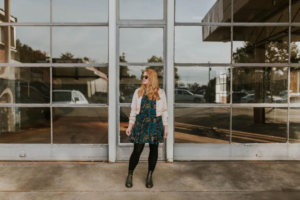 Free Image of Stylish woman leaning against glass windows 