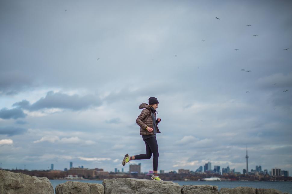Free Image of Woman running in urban outskirts with birds flying 