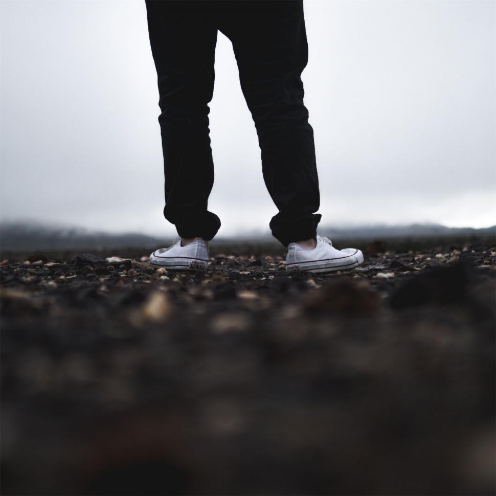 Free Image of Person in white sneakers standing on gravel 