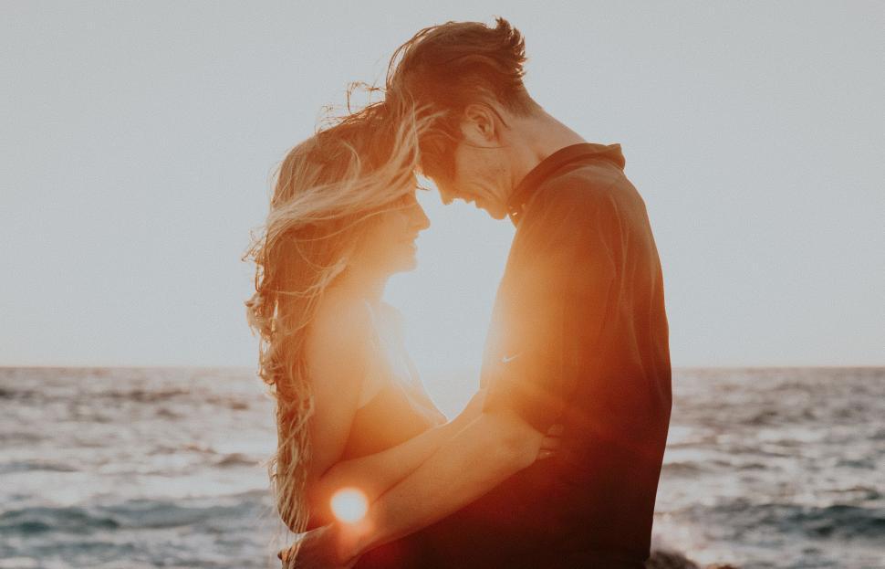 Free Image of Couple silhouette against the sunset at sea 