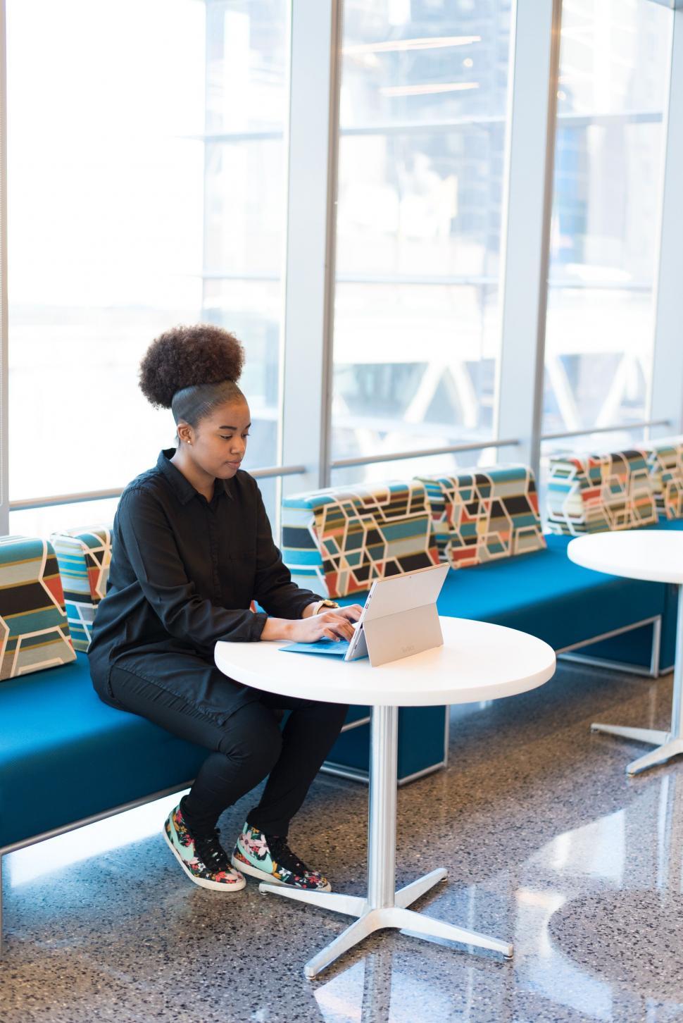 Free Image of Young woman studying on laptop in lounge 