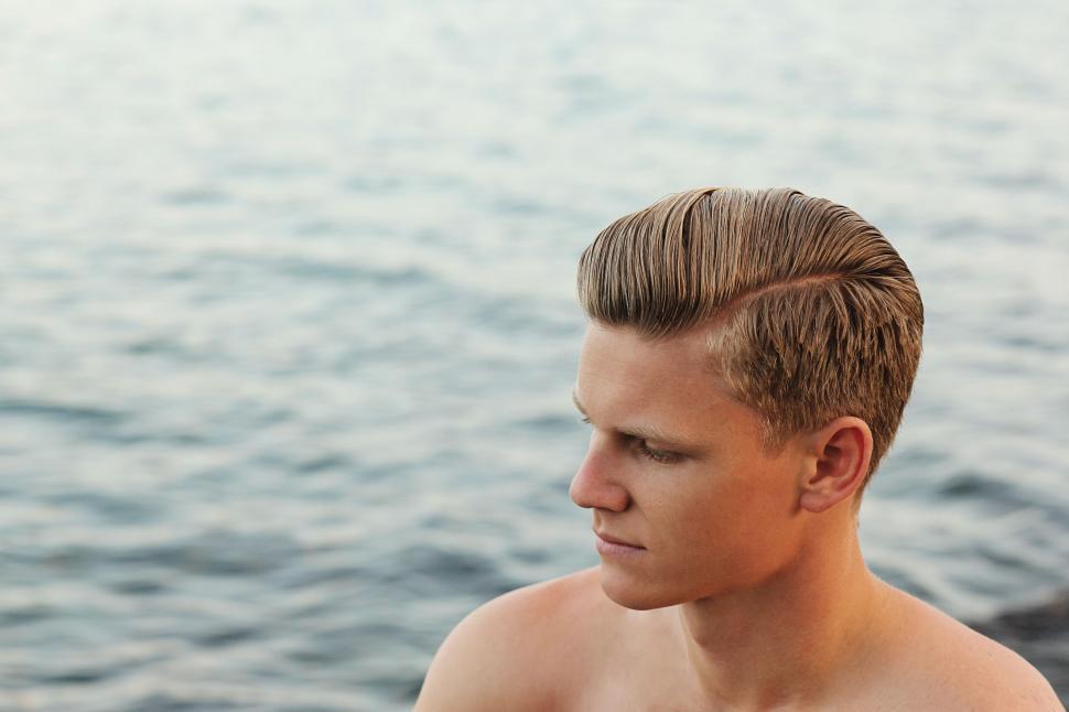 Free Image of Man sitting by serene ocean waters 