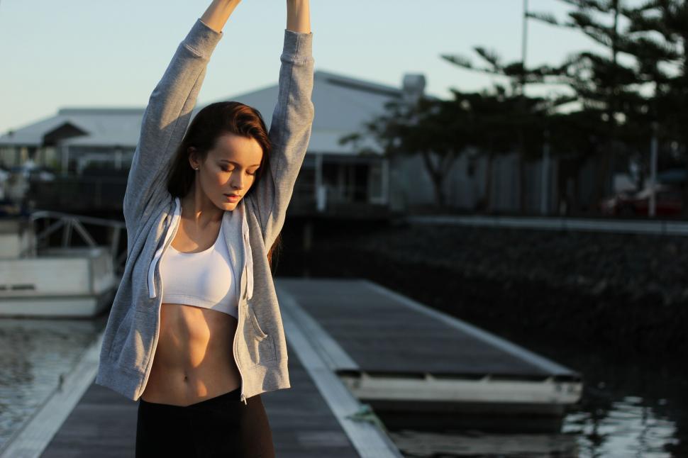Free Image of Fit woman stretching near a dock 