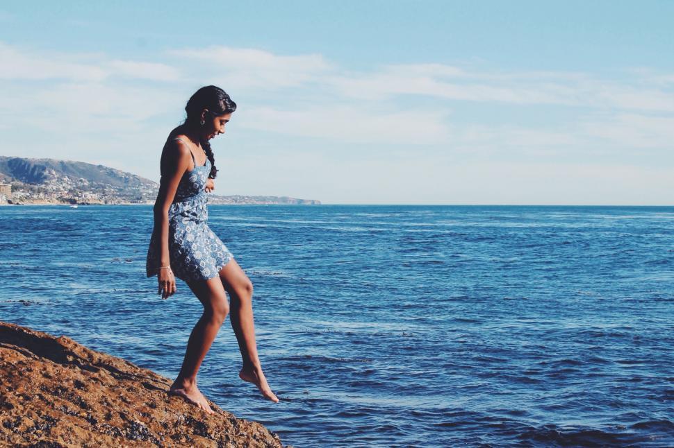 Free Image of Young woman on rocks looking out to sea 