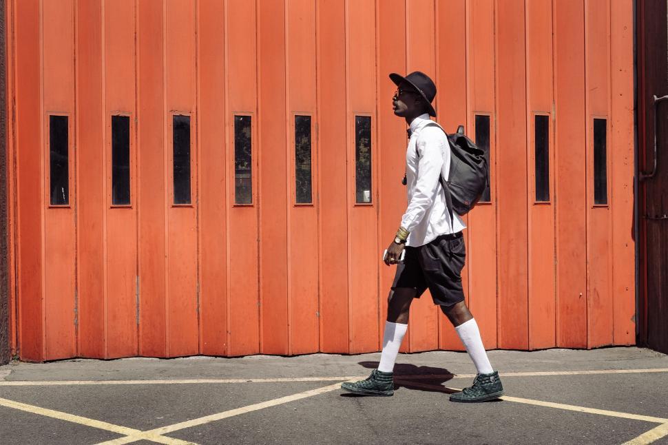 Free Image of Man walking past orange garage door 