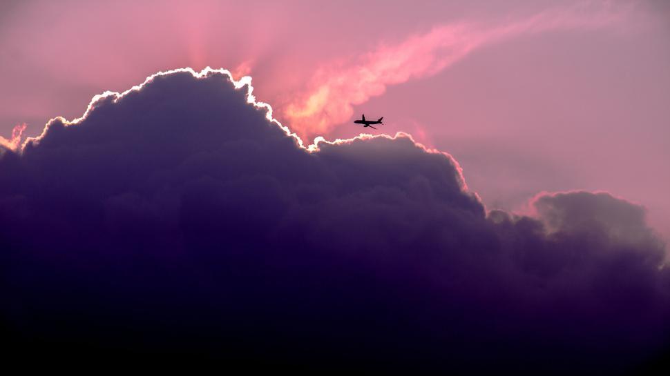 Free Image of Airplane silhouette against stunning sunset clouds 