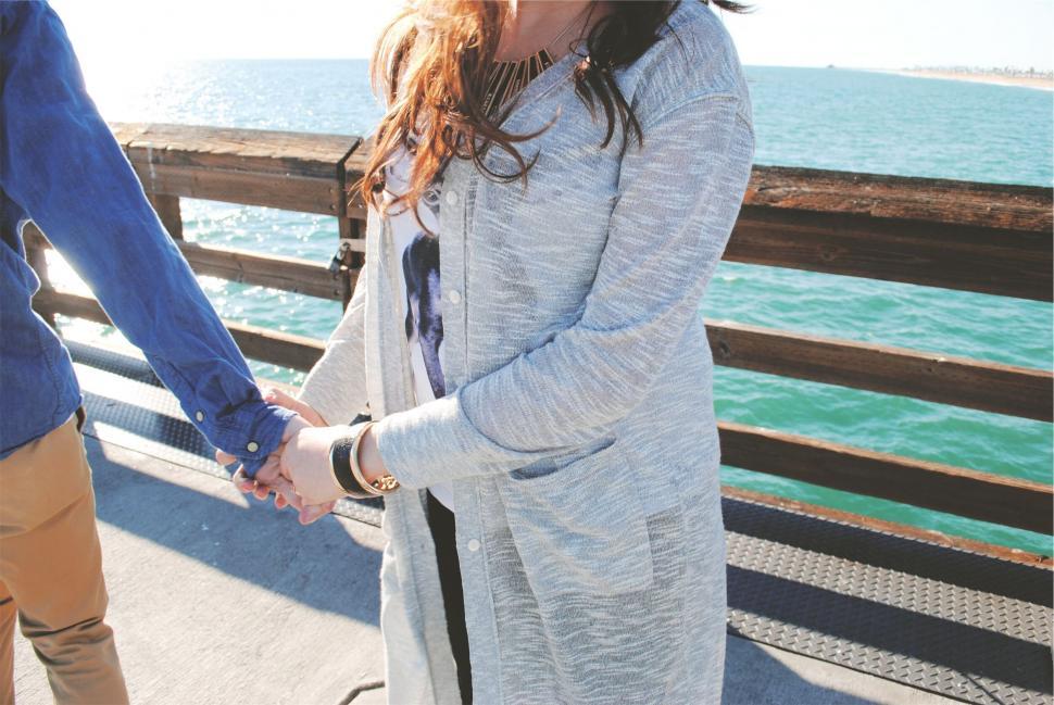 Free Image of Couple holding hands on a pier at sunset 