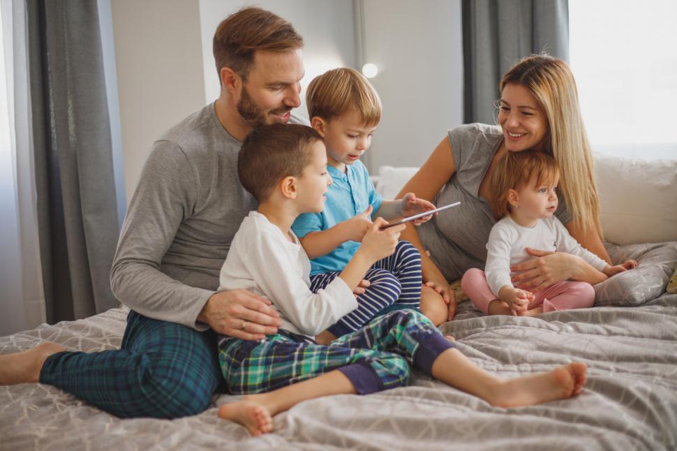 Free Image of Family relaxing with a tablet on the bed 