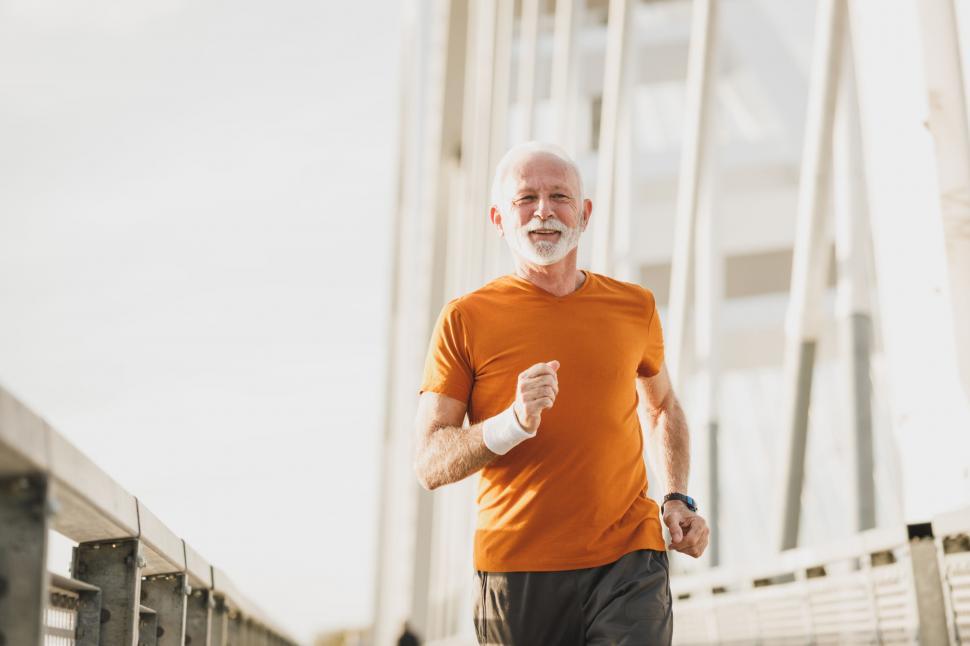 Free Image of Senior man jogging on a bridge at sunrise 