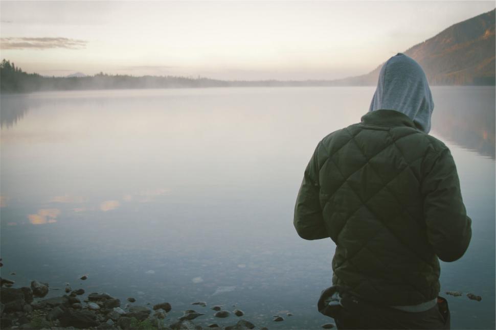 Free Image of Hooded figure gazing at a mist-covered lake 
