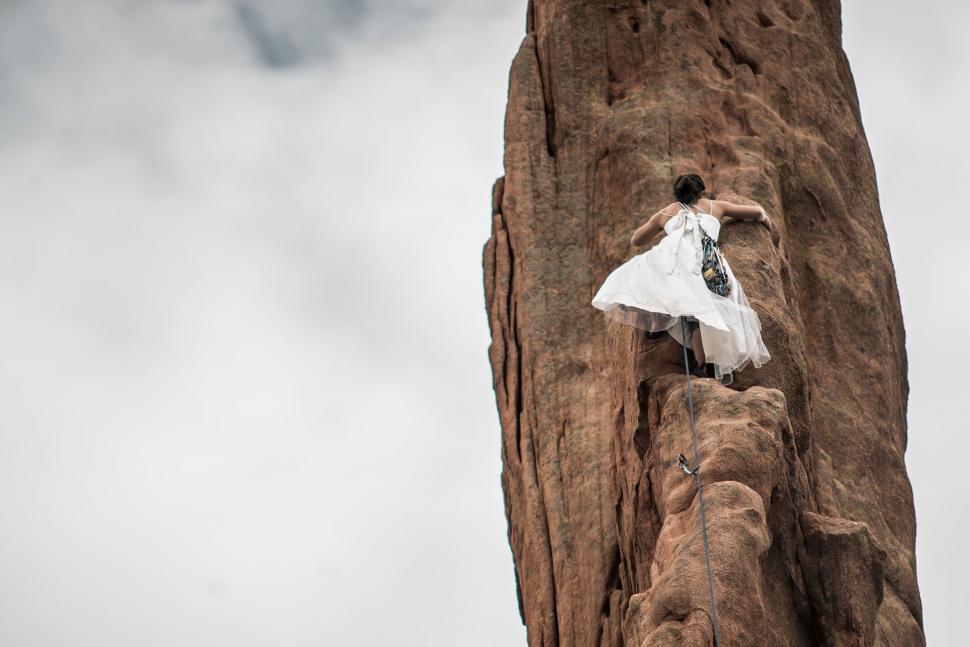 Free Image of Climber in dress on a red rock formation 