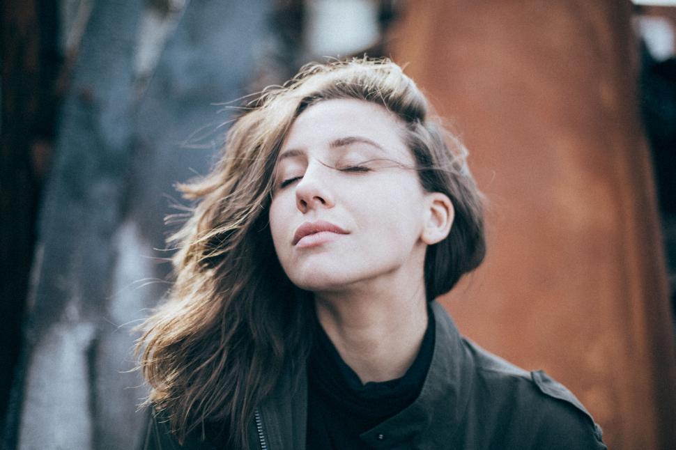 Free Image of Dreamy woman with eyes closed in urban backdrop 