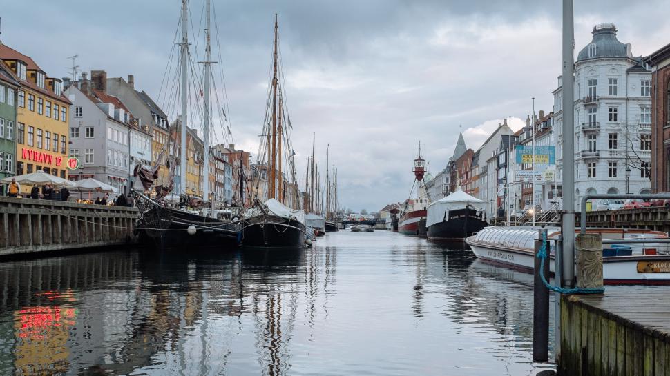 Free Image of Historic ships docked in a bustling city harbor 
