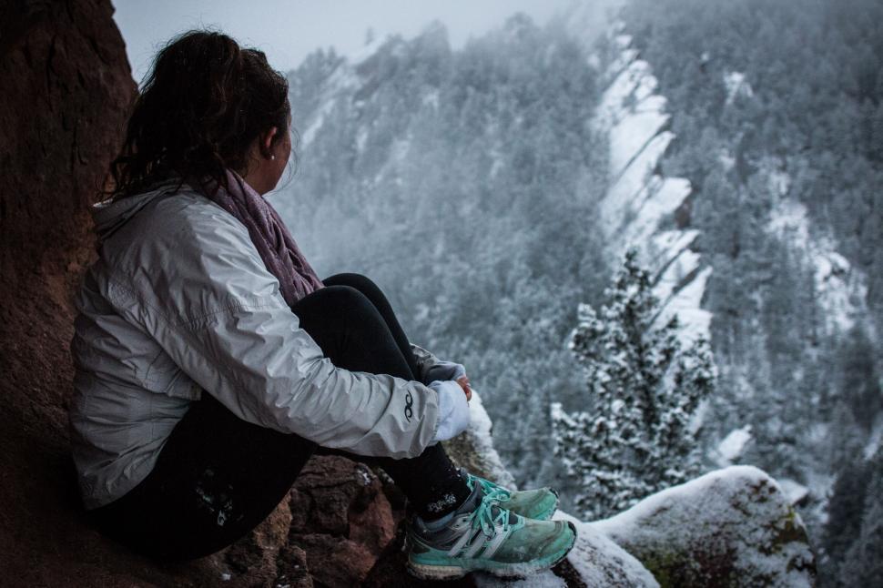 Free Image of Woman seated by a snowy cliff edge 
