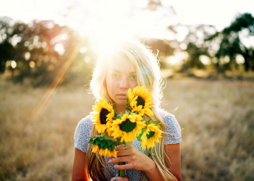 Free Image of Woman holding sunflowers in a field 