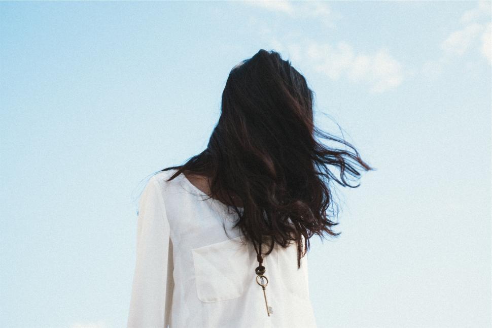 Free Image of Woman with blowing hair in the sky background 