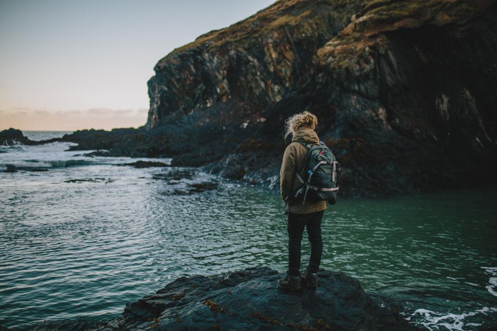 Free Image of Individual standing by the seaside on rocks 
