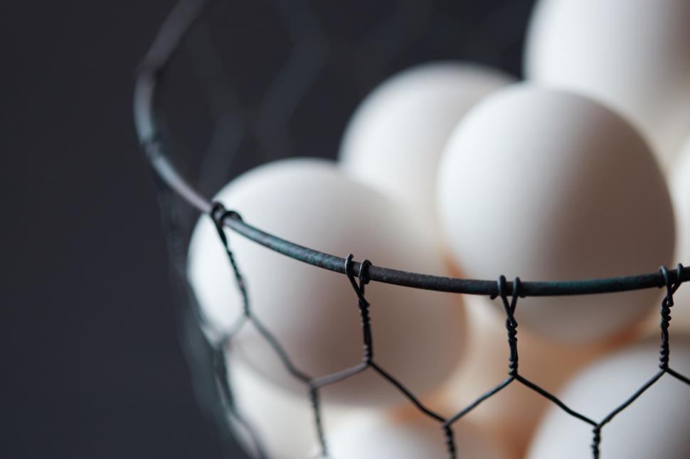 Free Image of White eggs nestled in wire basket closeup 