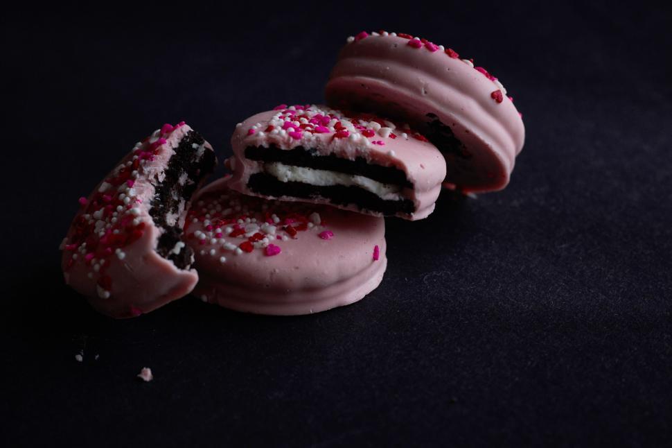 Free Image of Eaten pink macarons on a dark surface 