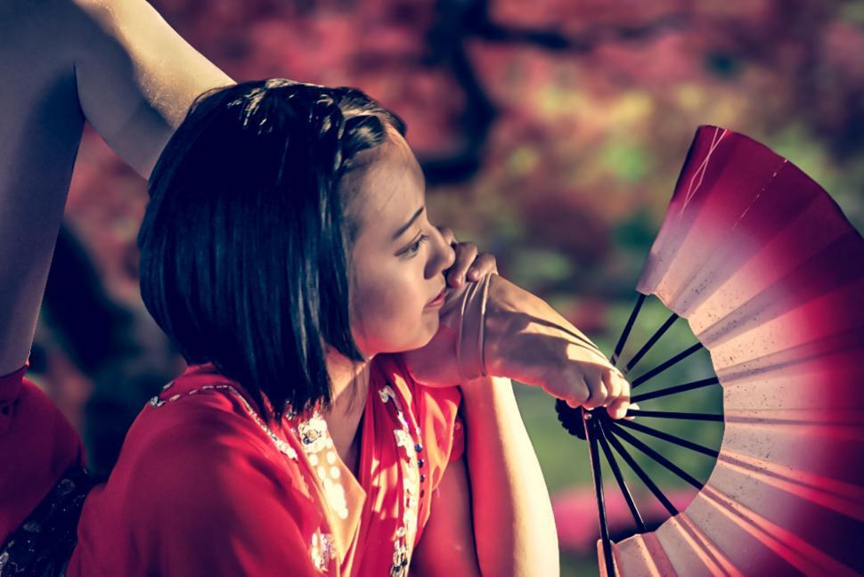 Free Image of Woman with fan covering face with blur effect 