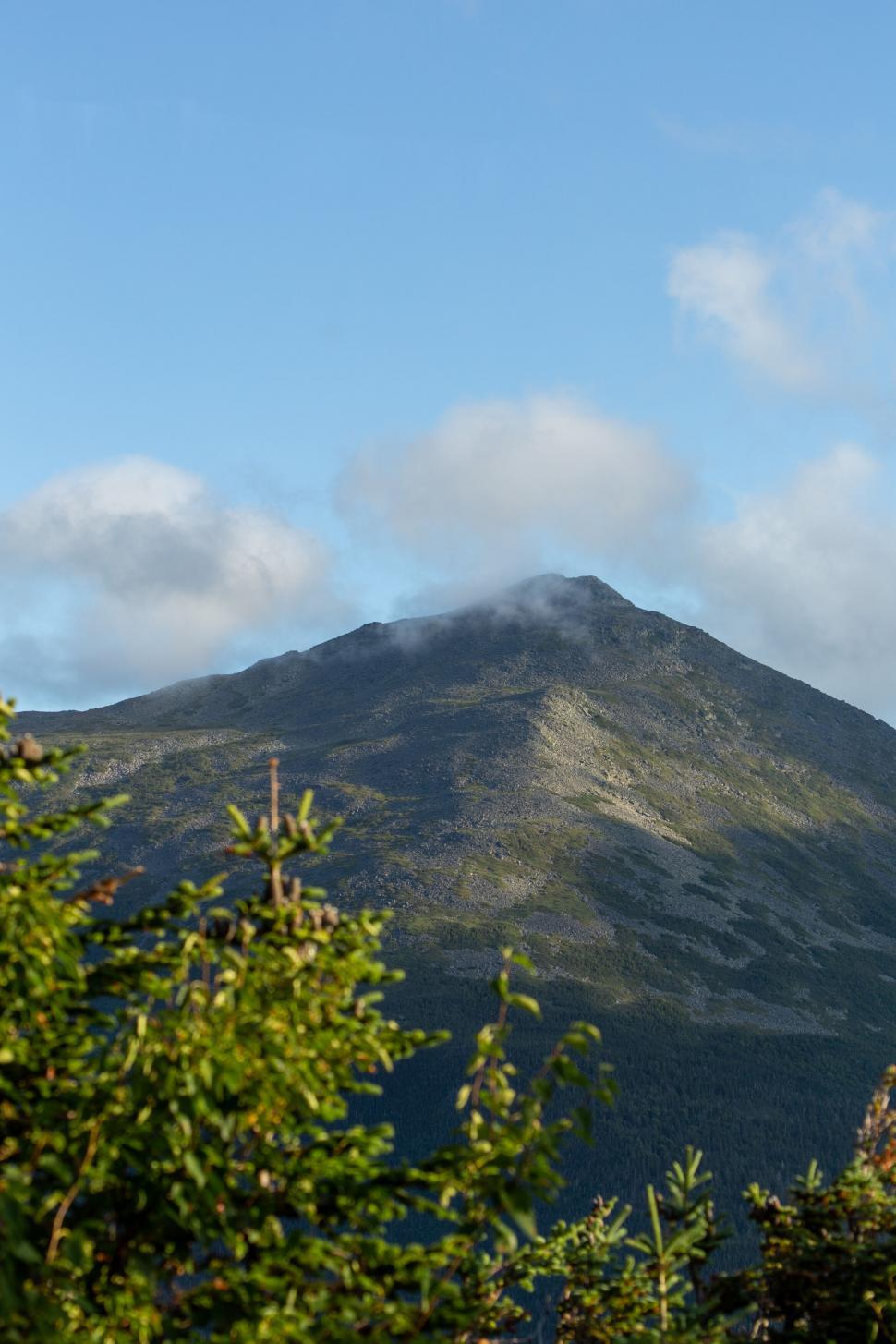 Free Image of Majestic mountain peak with clouds and foliage 