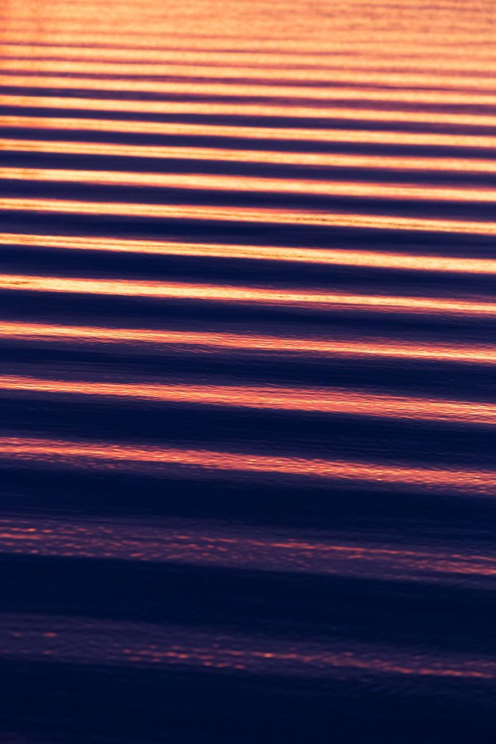 Free Image of Luminous sunset hues on rippled water 