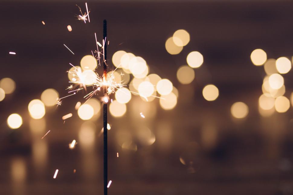 Free Image of Sparkler emitting sparks against bokeh lights 
