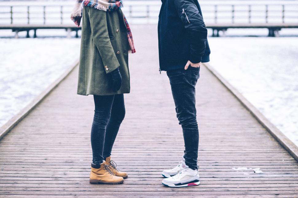 Free Image of Two people on a snowy wooden boardwalk 