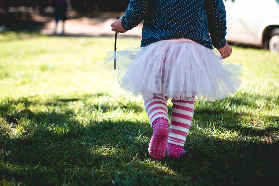 Free Image of Little girl walking in a tutu and striped socks 