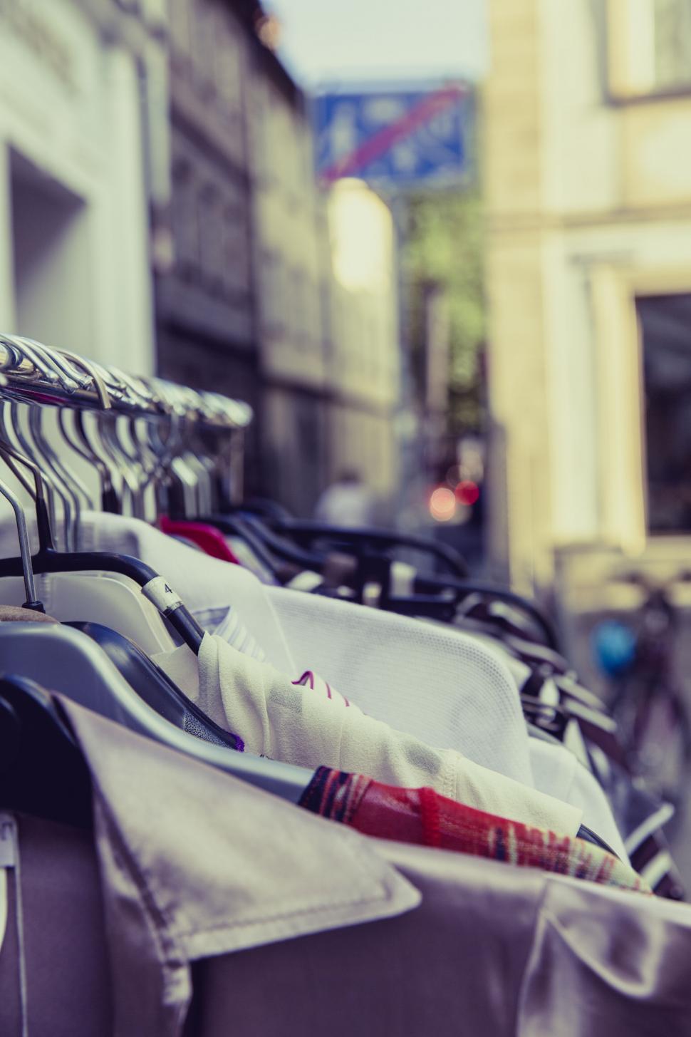 Free Image of Clothes hanging on a rack in the street 