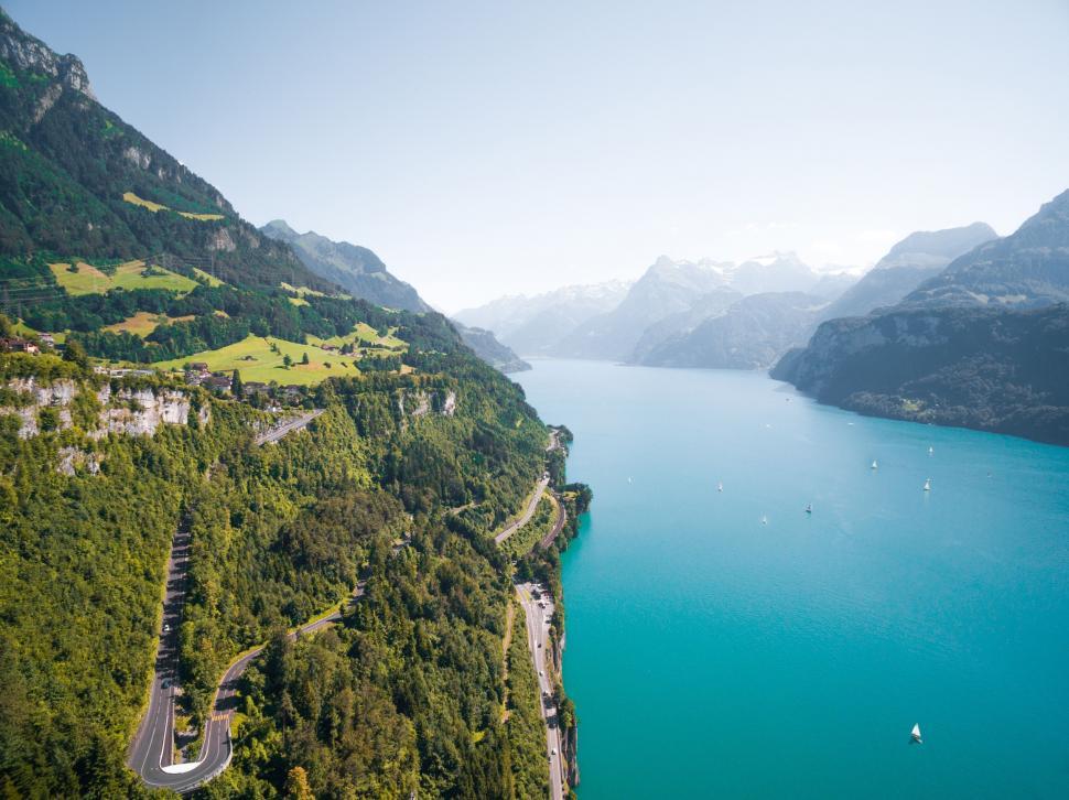 Free Image of Drone shot of serpentine road by turquoise lake 