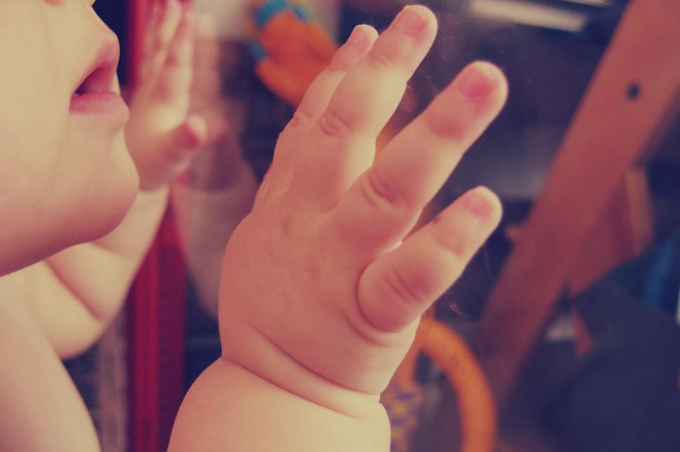 Free Image of Toddler s hand pressed against glass pane 