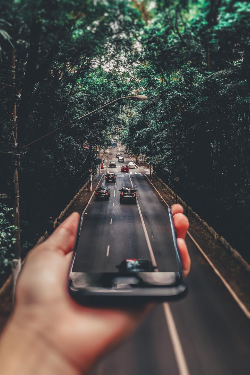 Free Image of Smartphone Blurring Road into Forest Scene 