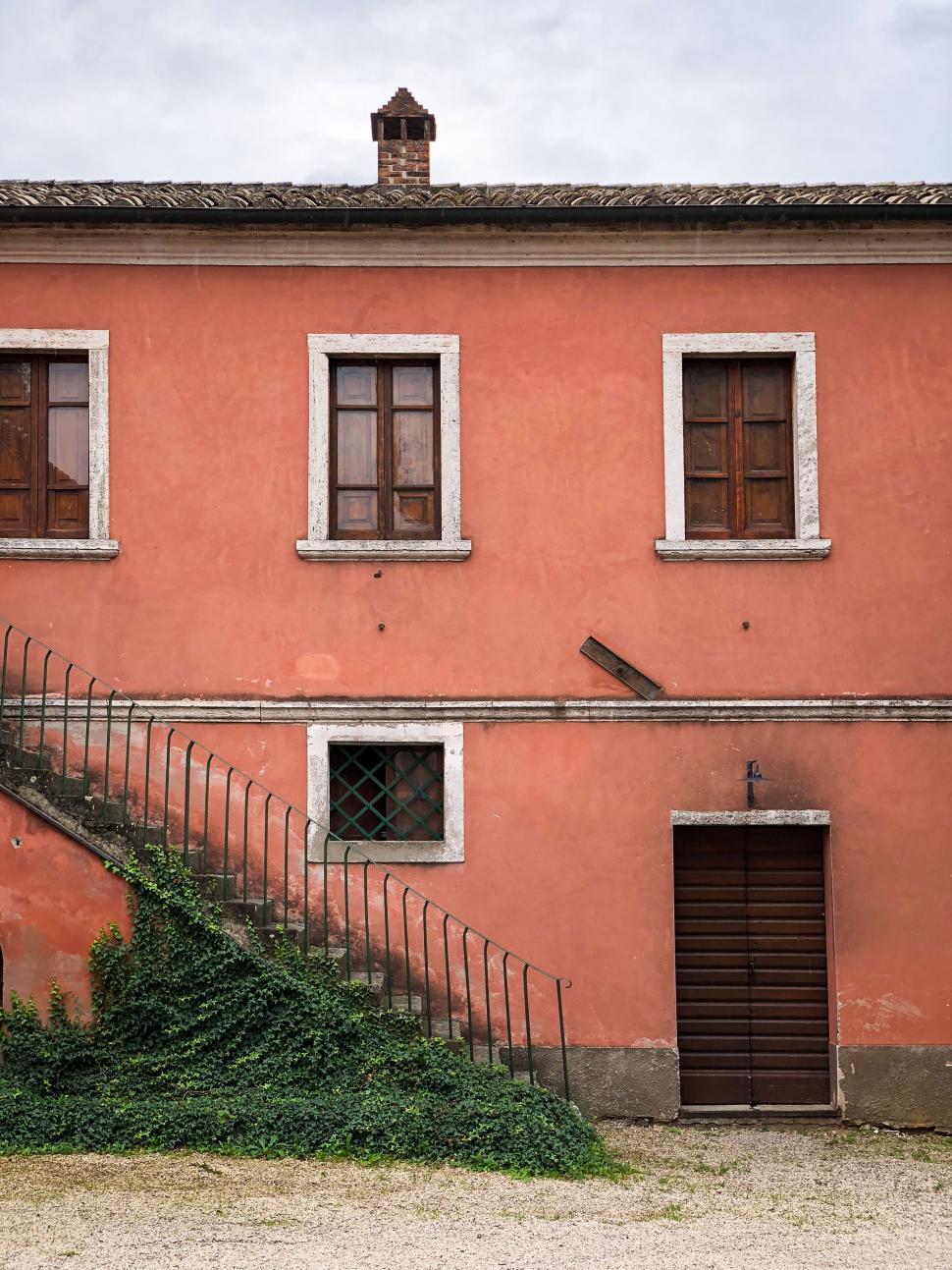 Free Image of Old orange house with green shutters and stairs 