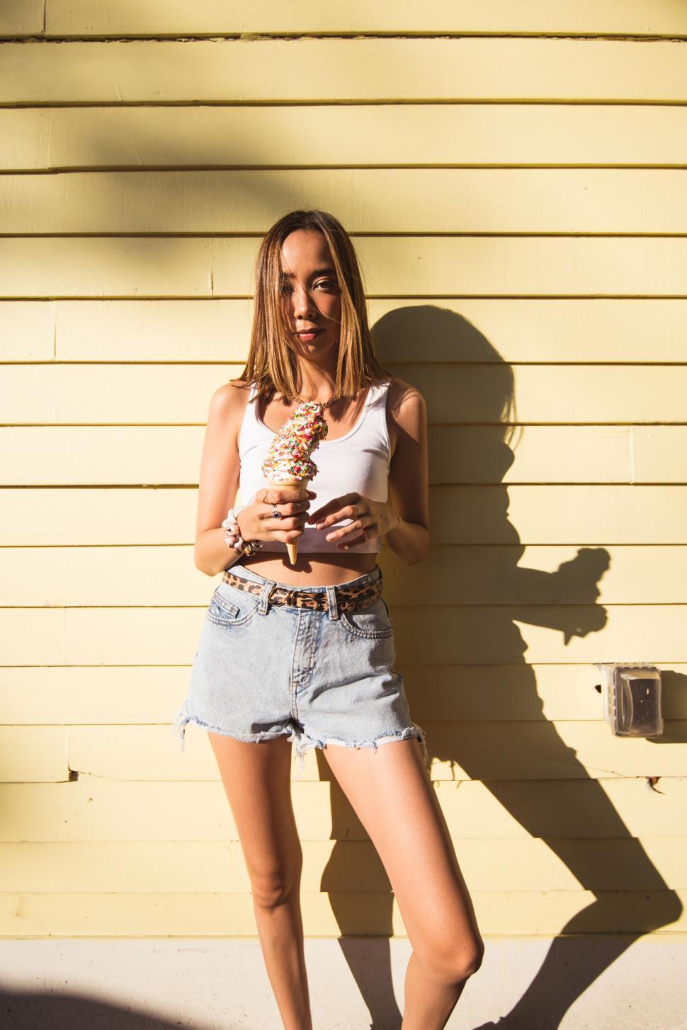 Free Image of Woman with ice cream against yellow wall 