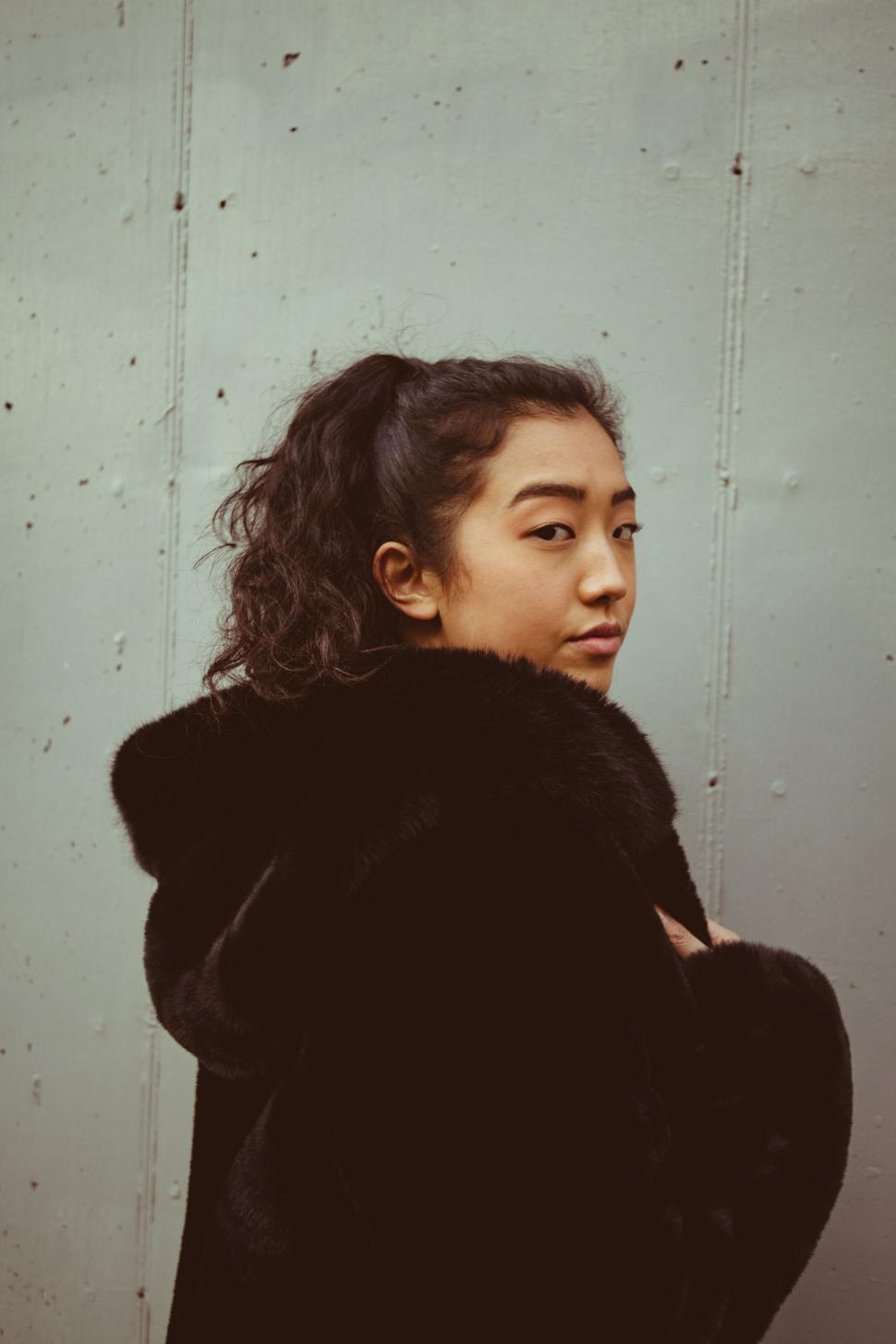 Free Image of Woman in winter coat against wall 