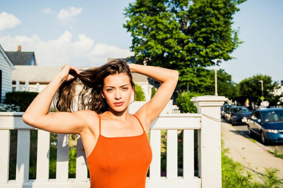 Free Image of Woman adjusting hair in orange tank top 