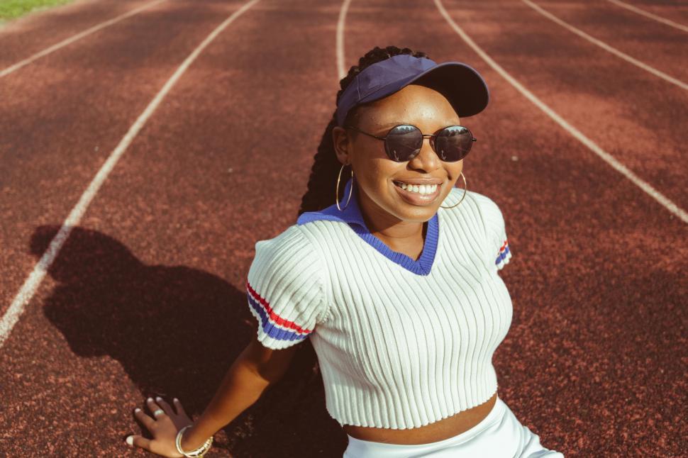 Free Image of Happy woman kneeling on a running track 