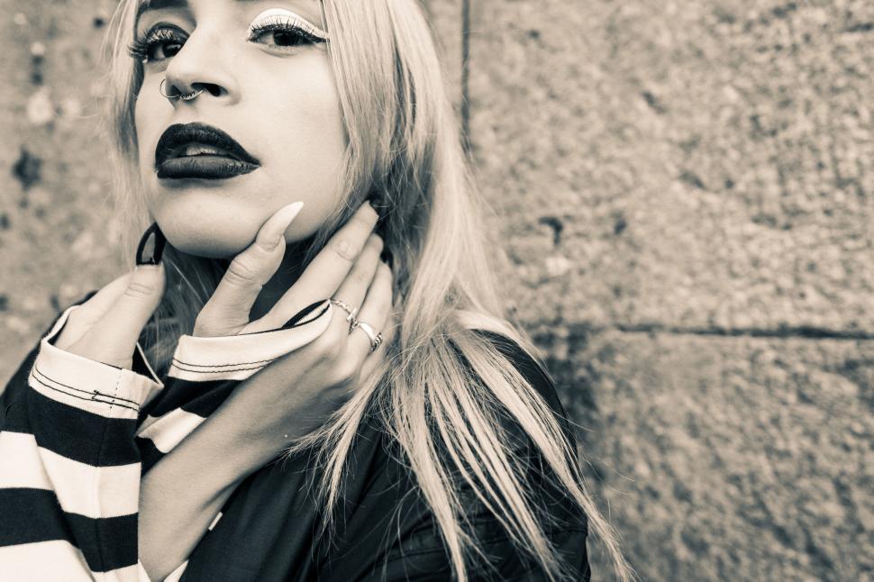 Free Image of Blond woman in striped garment holding neck 