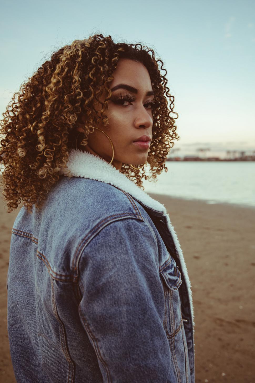 Free Image of Woman in denim jacket on beach 