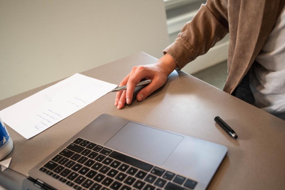 Free Image of Man working on laptop with documents 
